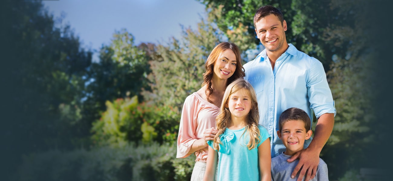 Husband and wife with two kids outside on crisp summer day.