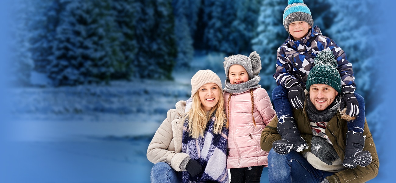 Husband and wife with two kids outside in snowy conditions, bundled up for winter.