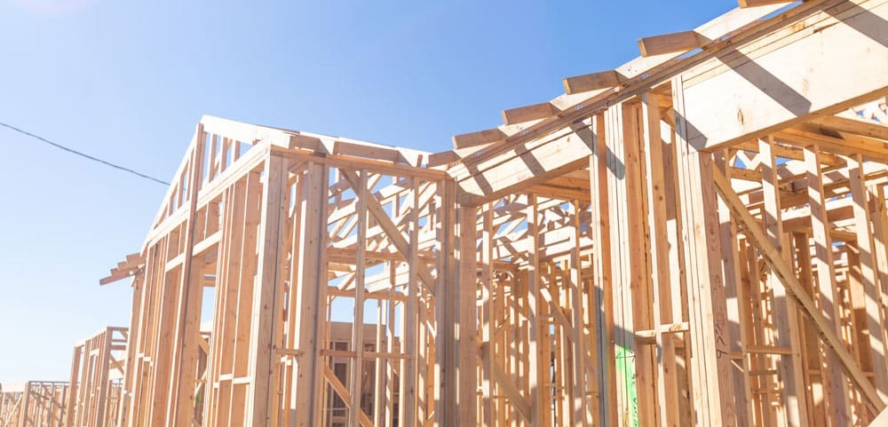 Exterior shot of the early stages of a new home being built, all wooden framework and studs.