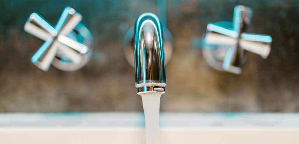 Front view of a faucet pouring water into a basin in a residential bathroom.